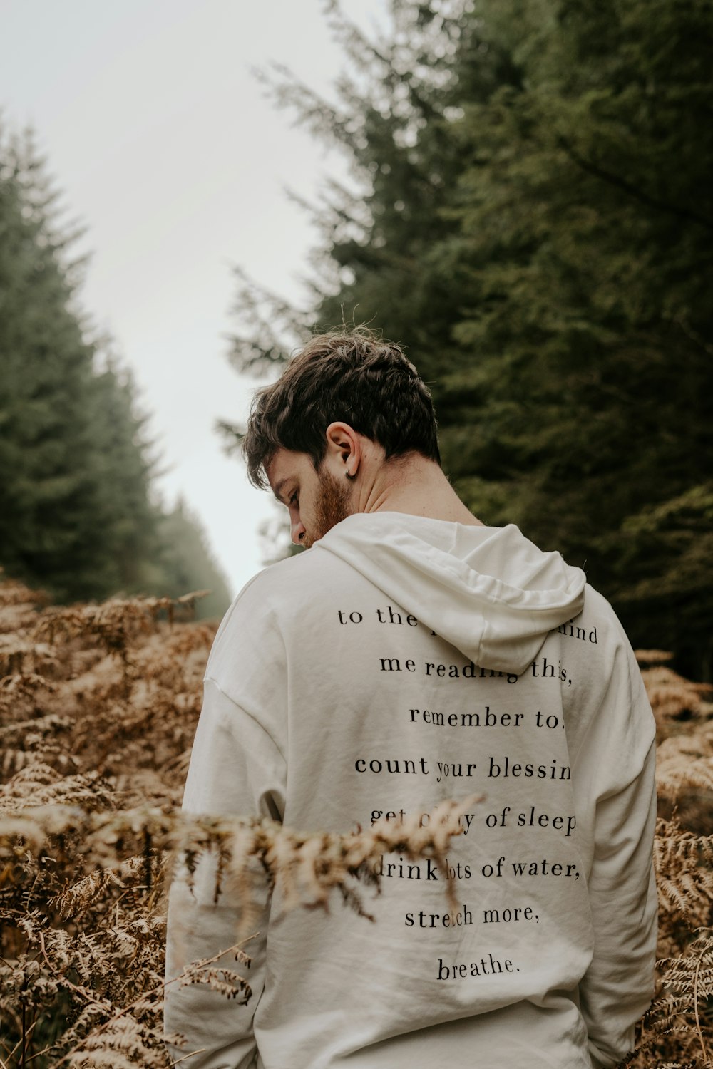 man in white shirt standing on brown dried leaves during daytime