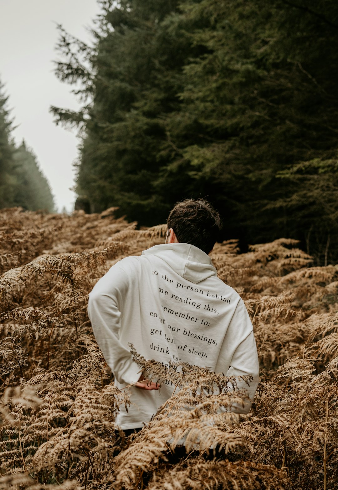 man in white robe sitting on brown grass field during daytime