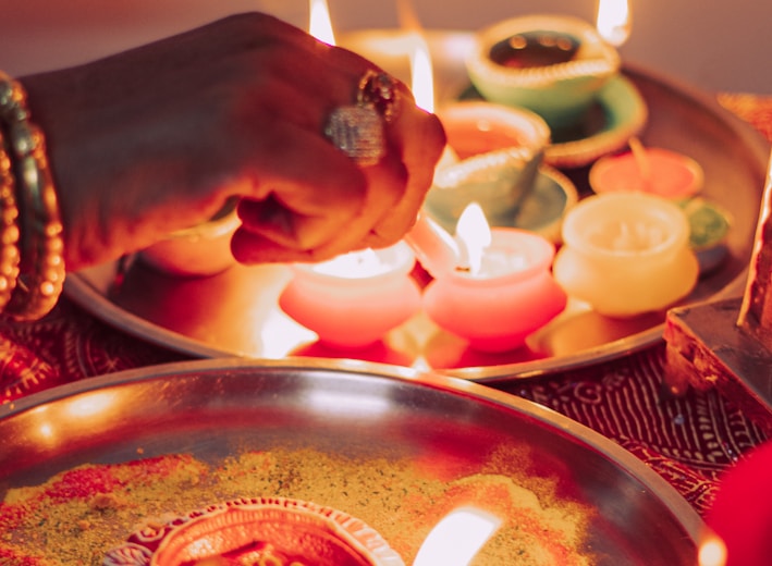 person holding lighted candle on brass round tray