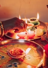 person holding lighted candle on brass round tray