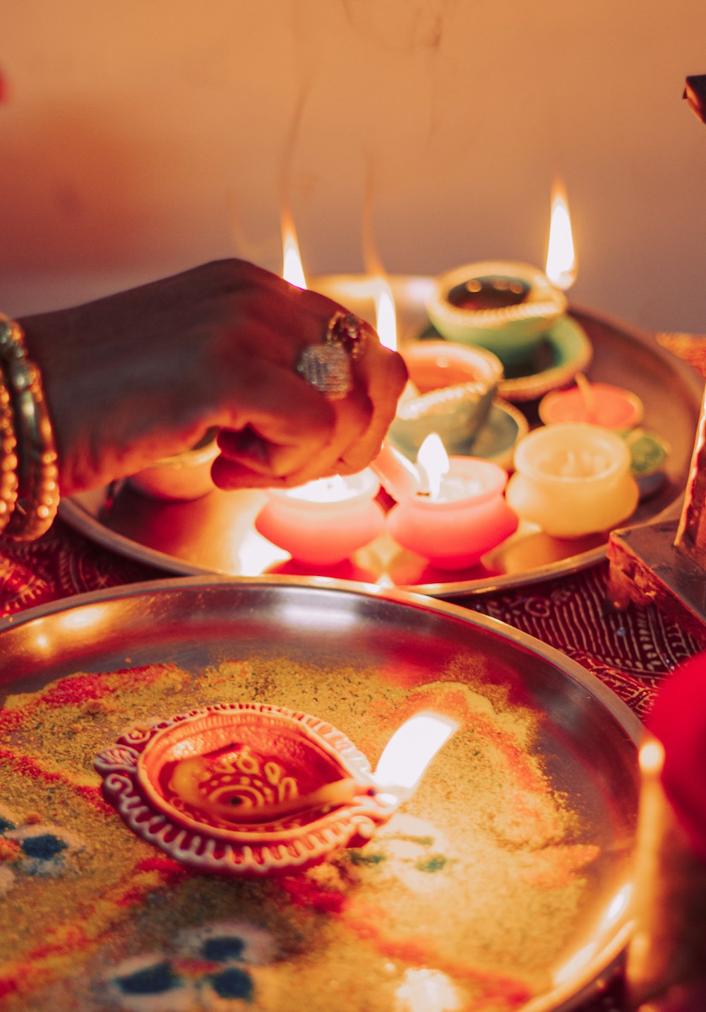 person holding lighted candle on brass round tray