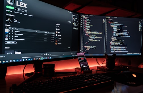 A developer coding a custom music streaming app on dual monitors.