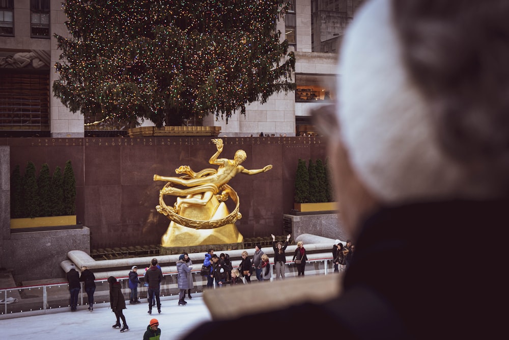 people standing in front of gold statue