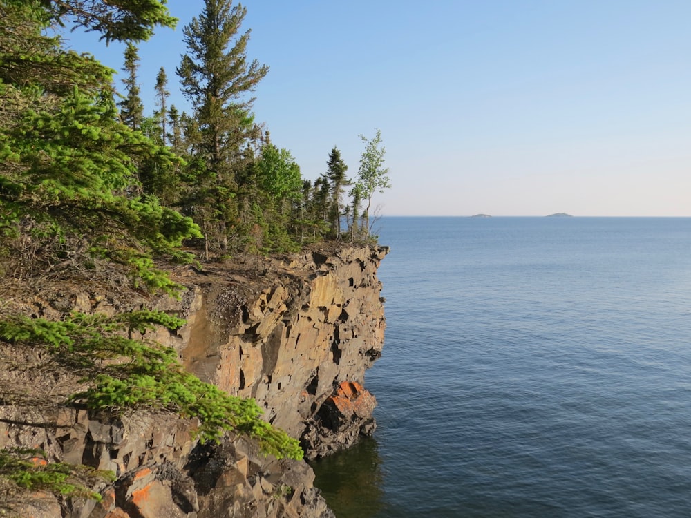 brown rocky mountain beside blue sea under blue sky during daytime