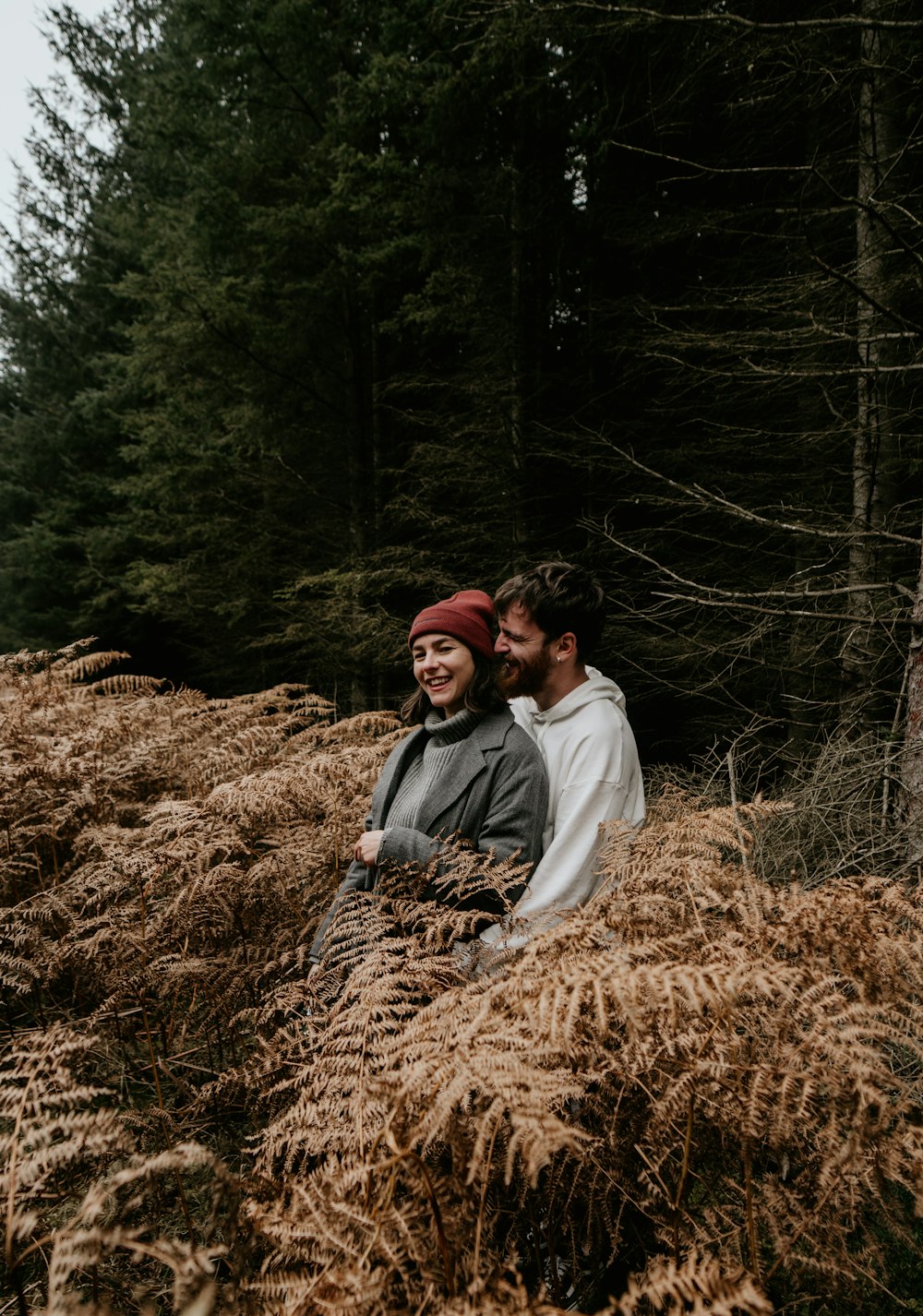 couple sitting on brown dried grass during daytime