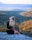 woman in black dress sitting on rock looking at the sea during daytime