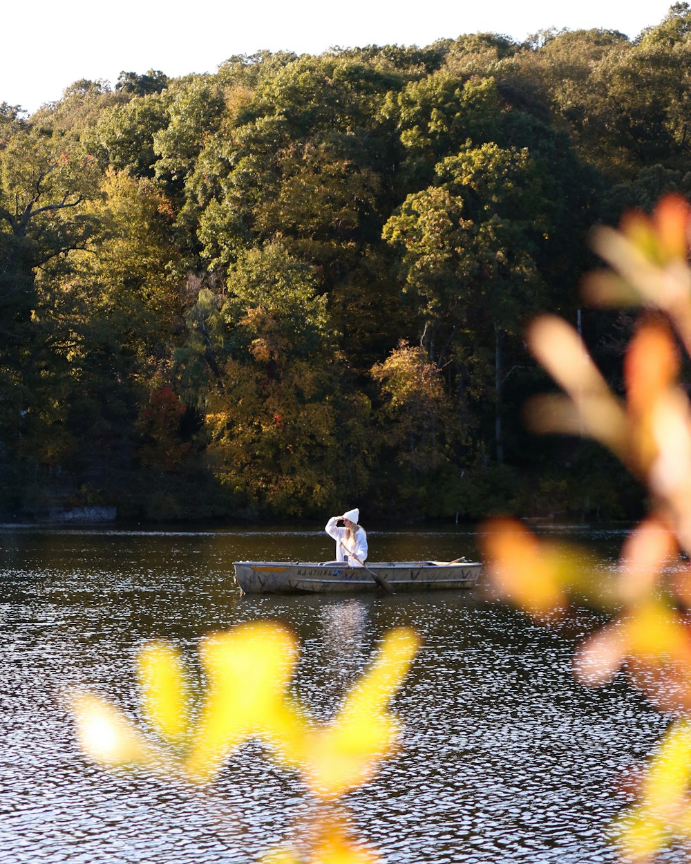 woman in white dress sitting on gray concrete bench near river during daytime