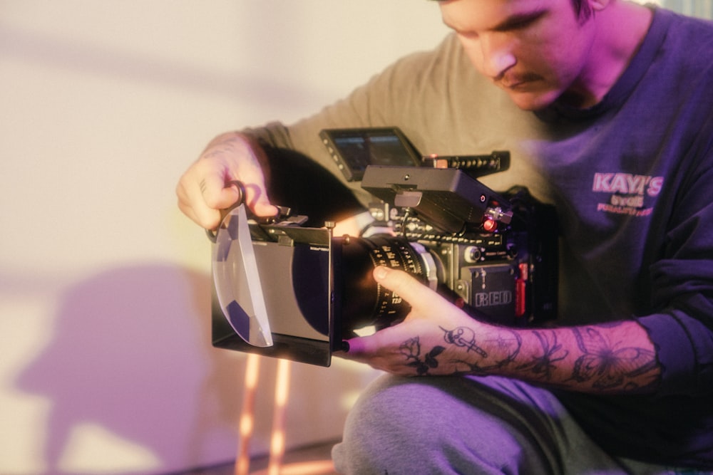 man in gray sweater using black video camera