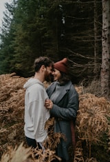 man and woman kissing on brown grass field during daytime