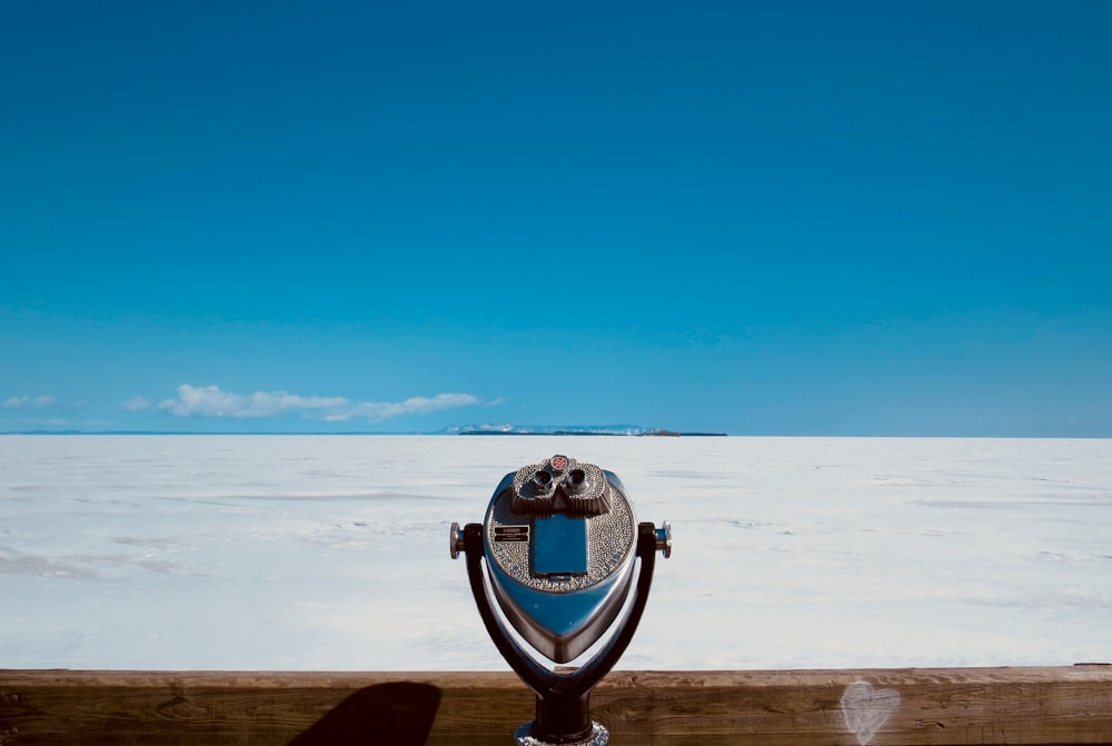 blue and silver coin operated binoculars on brown wooden table