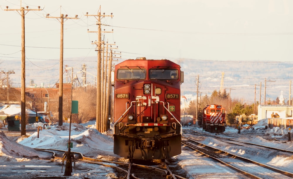red train on rail road covered with snow during daytime