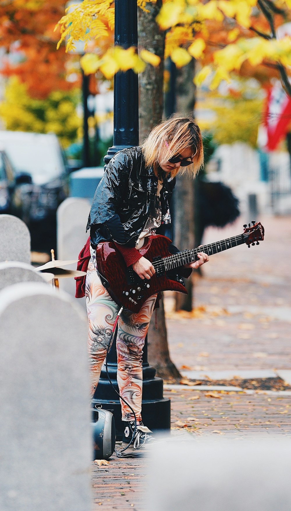 woman in black jacket playing red electric guitar