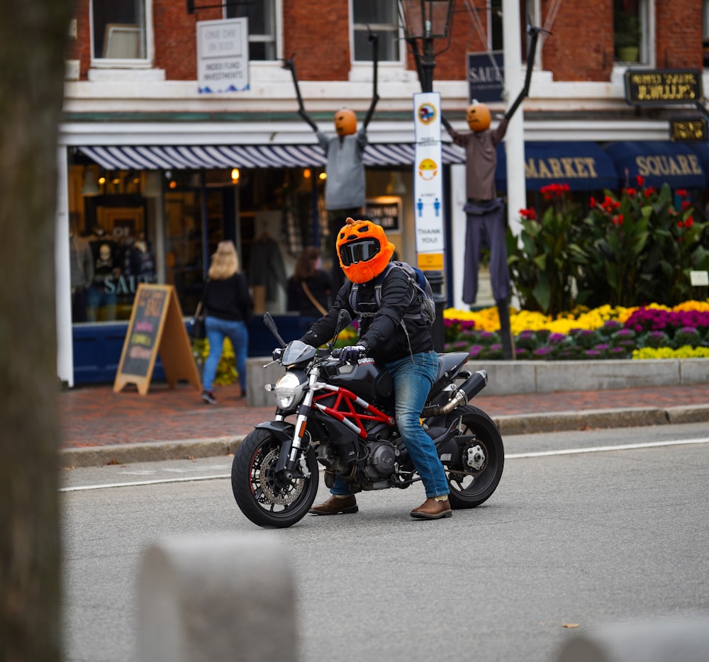 man in orange helmet riding black motorcycle on road during daytime