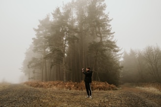 A candid photo of a young person exploring a misty forest trail at dusk.