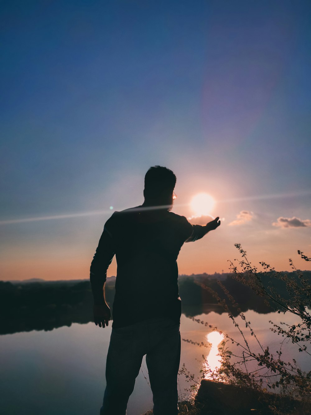 silhouette of man standing on grass field during sunset