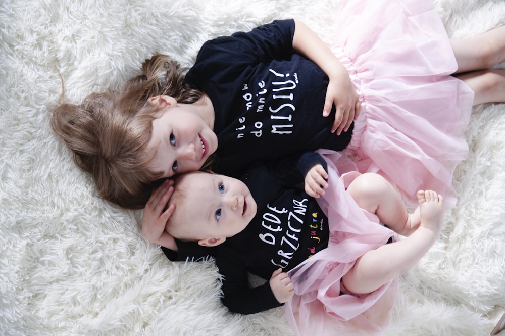 2 girls lying on white fur textile