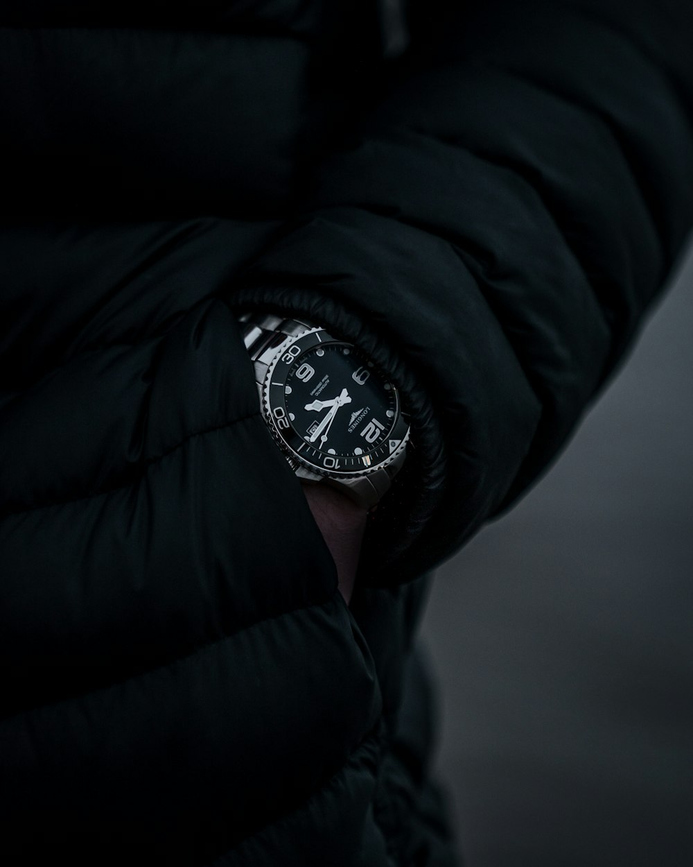 person wearing black leather jacket and black and white chronograph watch