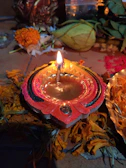 Close-up of a glowing diya lamp surrounded by marigold flowers and sacred threads.