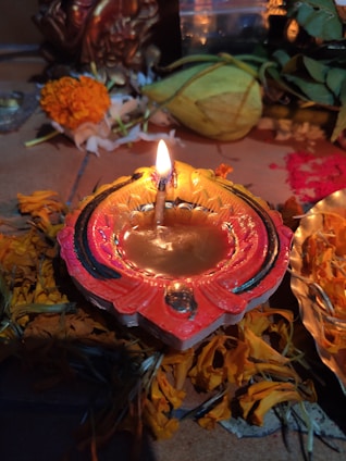 A rustic arrangement of natural cow dung cakes stacked neatly beside blooming marigold flowers and traditional brass pooja items.