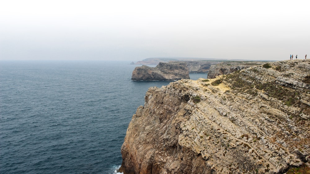 brown rocky mountain beside sea during daytime