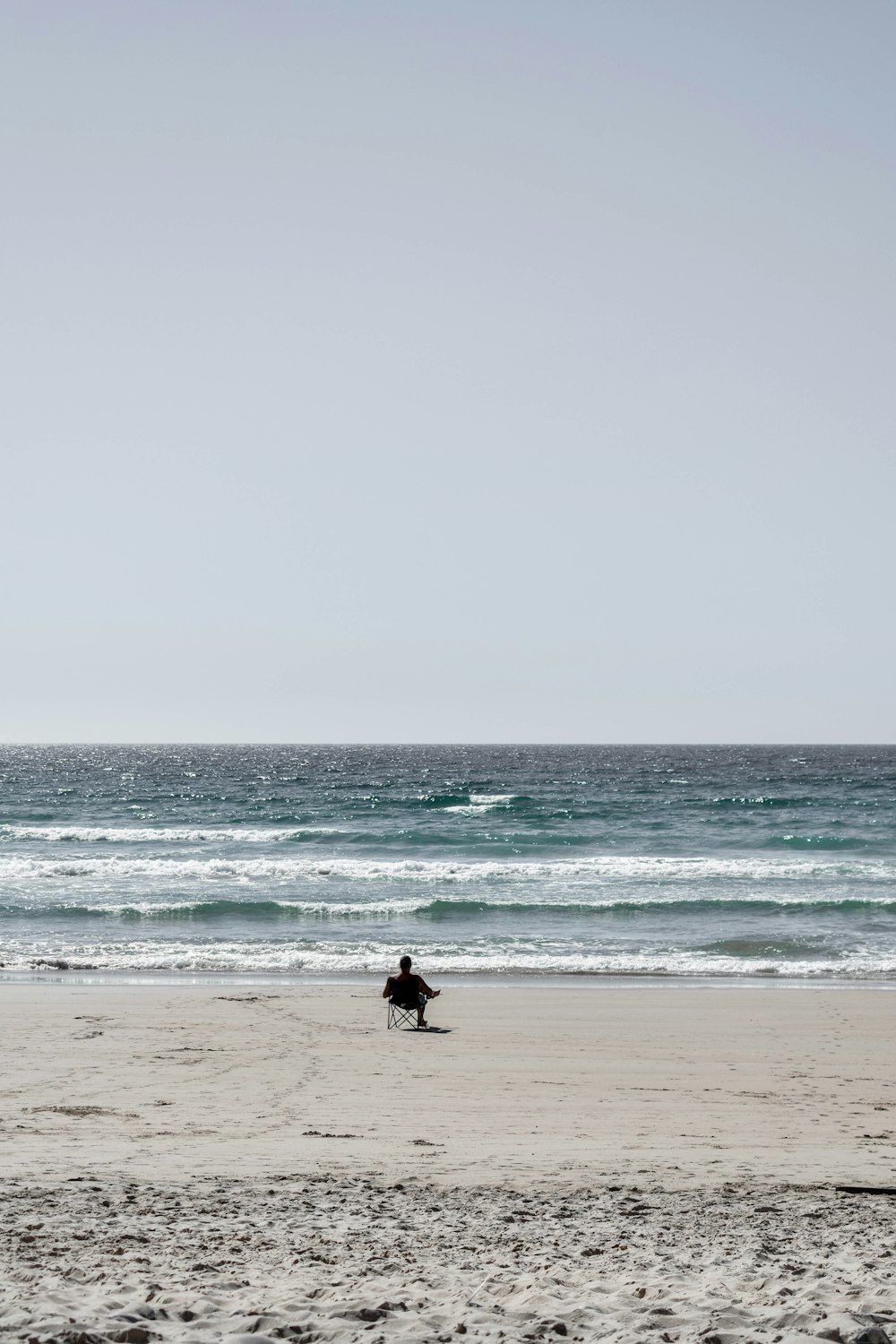 person in black wet suit carrying white surfboard walking on beach during daytime