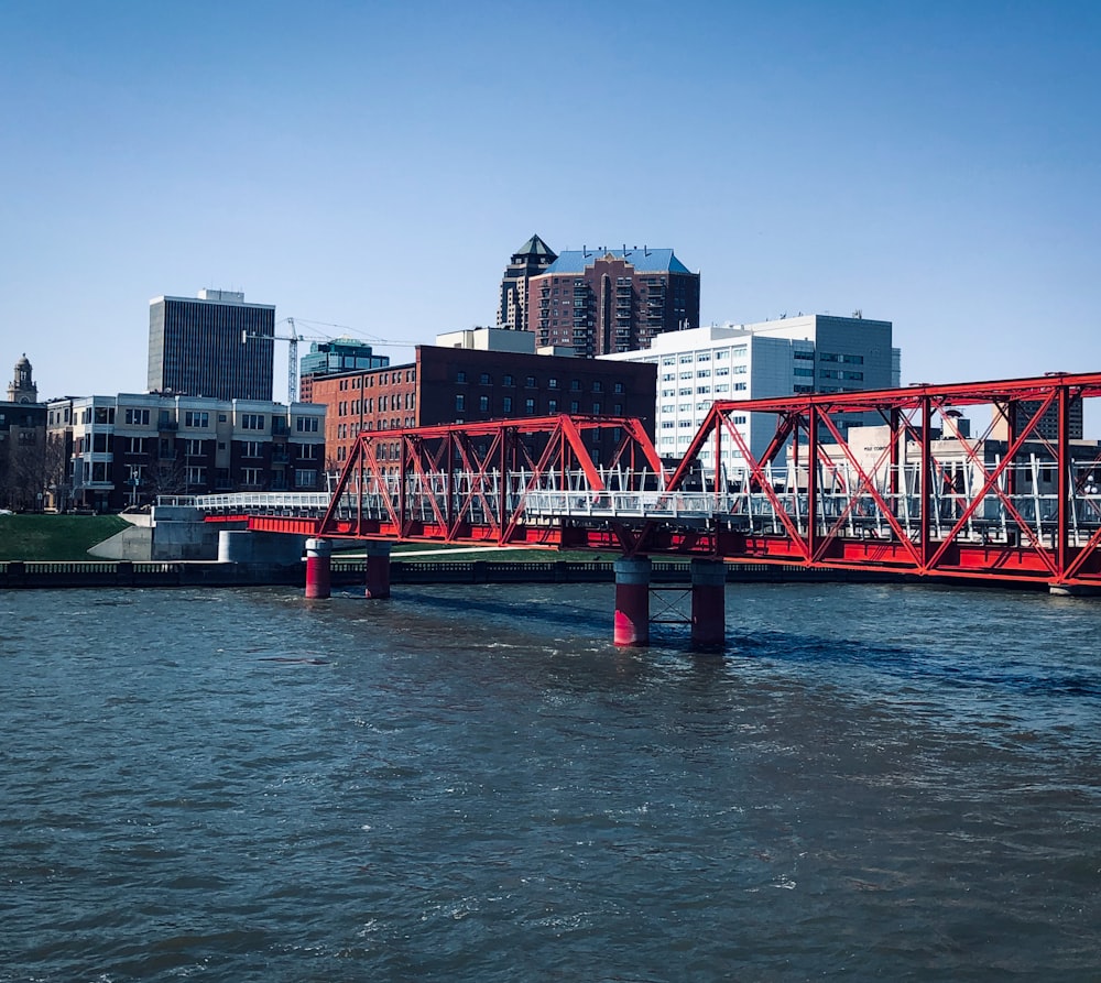 red bridge over water near city buildings during daytime