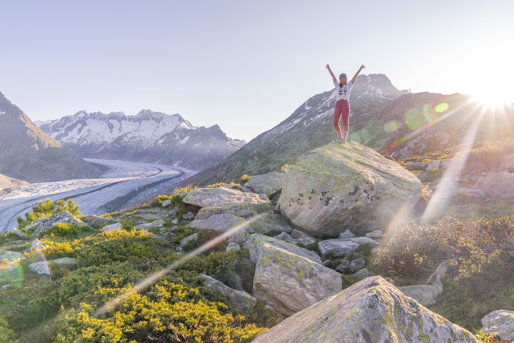 person in red long sleeve shirt standing on gray rock during daytime