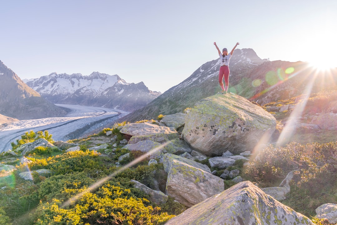 person in red long sleeve shirt standing on gray rock during daytime