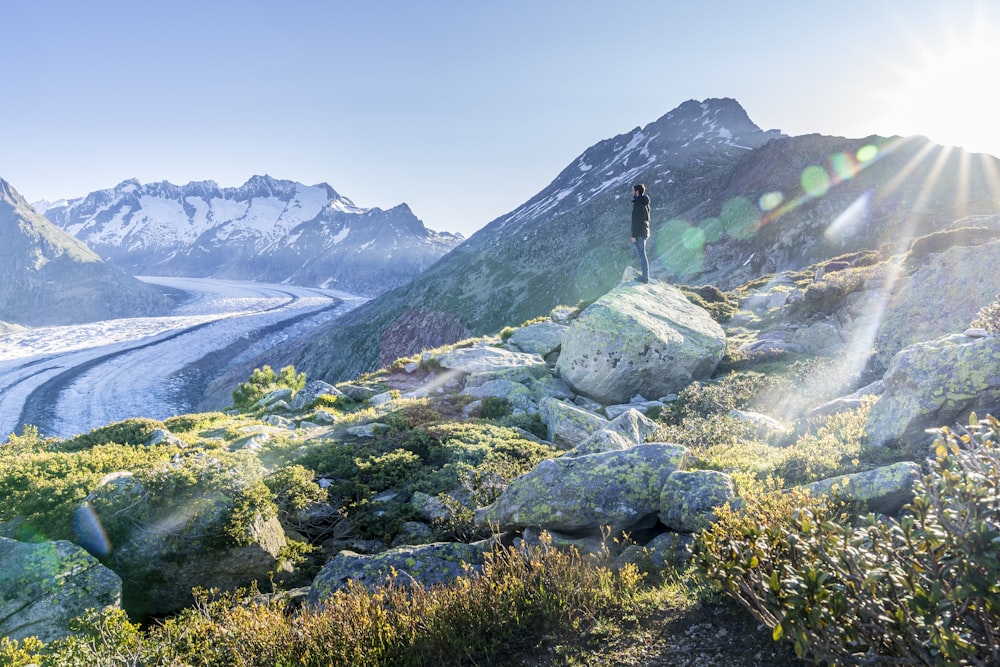pessoa em pé na rocha perto da montanha durante o dia
