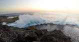 Ocean waves crashing against rocky cliffs during sunset.
