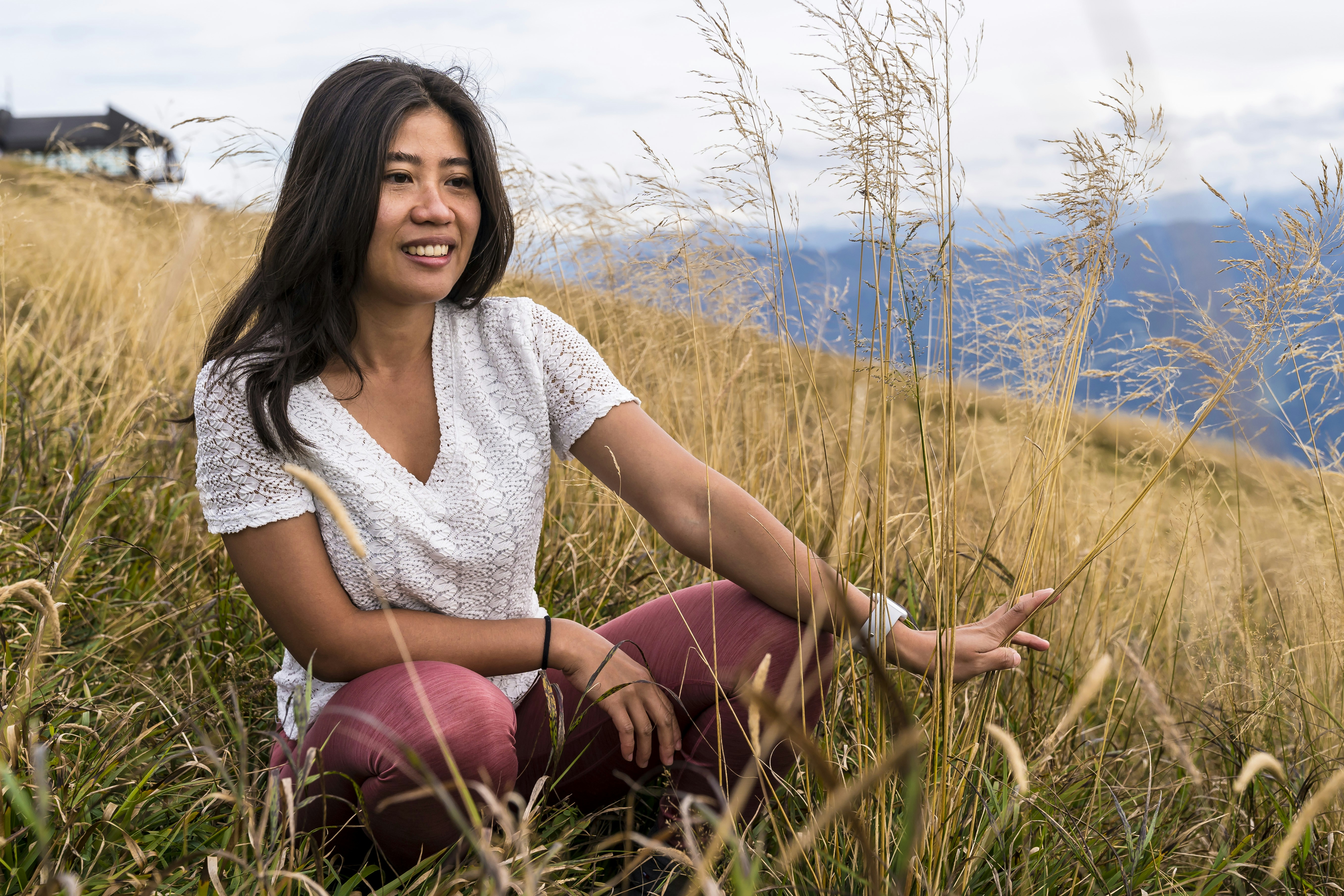 woman in white shirt sitting on grass field during daytime