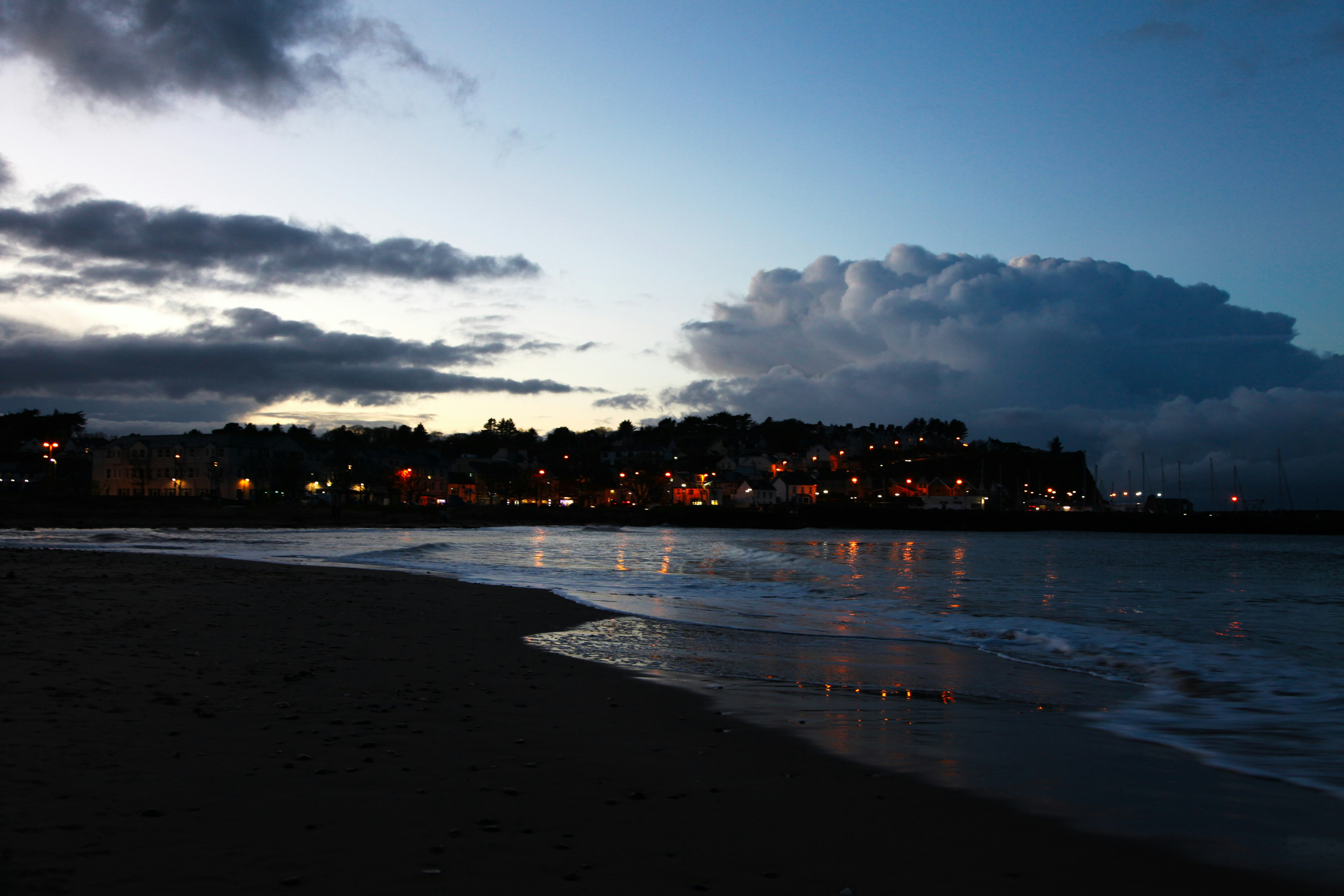 Town lights reflecting on a beach at dusk