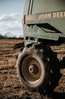 A farmer fitting durable agricultural equipment accessories onto a tractor in a sunny field.