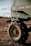 A close-up of a large agricultural machine with the branding visible, displaying sturdy tires resting on a grassy field under a partly cloudy sky. The machinery appears robust, equipped for fieldwork.