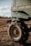 A close-up of a large agricultural machine with the branding visible, displaying sturdy tires resting on a grassy field under a partly cloudy sky. The machinery appears robust, equipped for fieldwork.