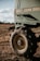 A close-up of a large agricultural machine with the branding visible, displaying sturdy tires resting on a grassy field under a partly cloudy sky. The machinery appears robust, equipped for fieldwork.
