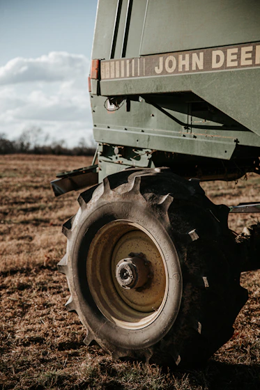 A farmer inspecting agricultural machinery parts in a sunny field.