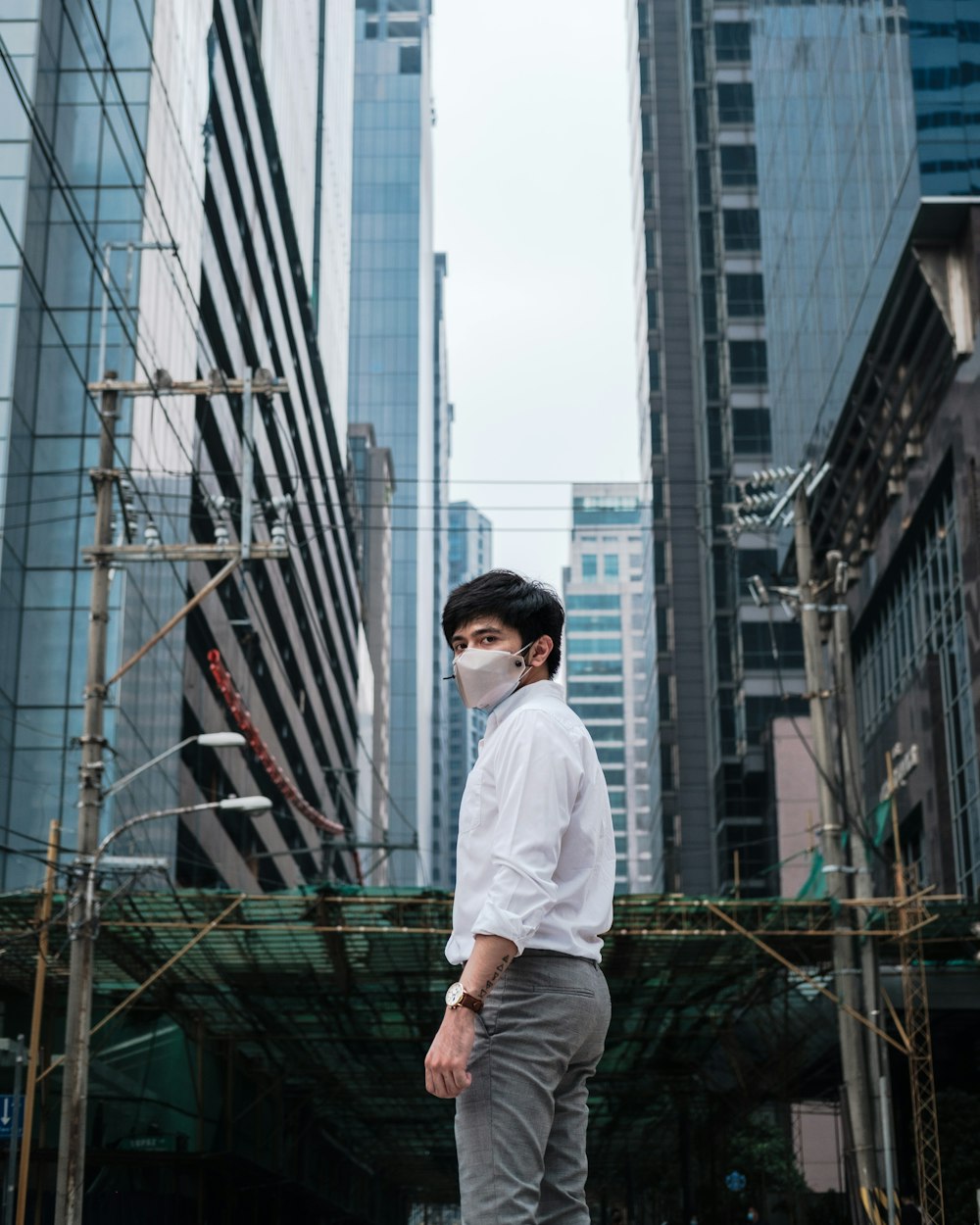 man in white dress shirt and black pants standing on top of building during daytime