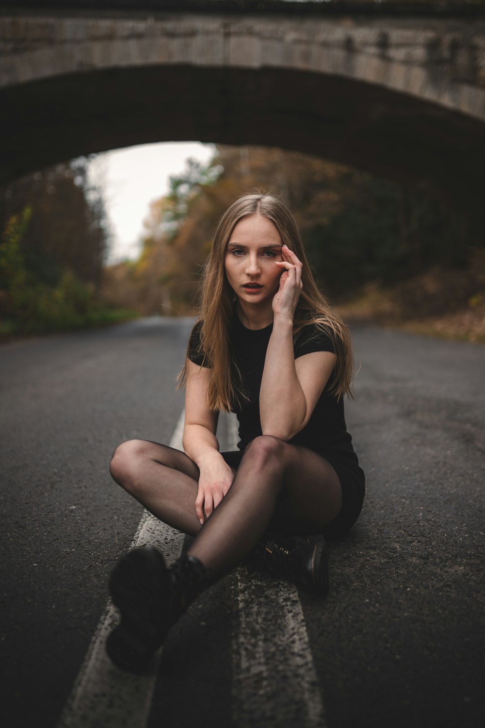 woman in black tank top sitting on road during daytime