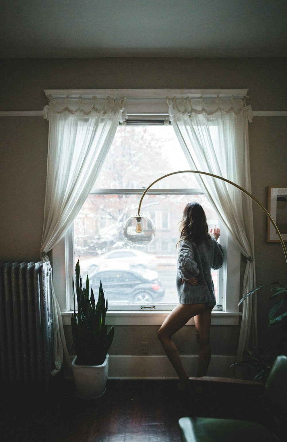 woman in gray shirt standing near window