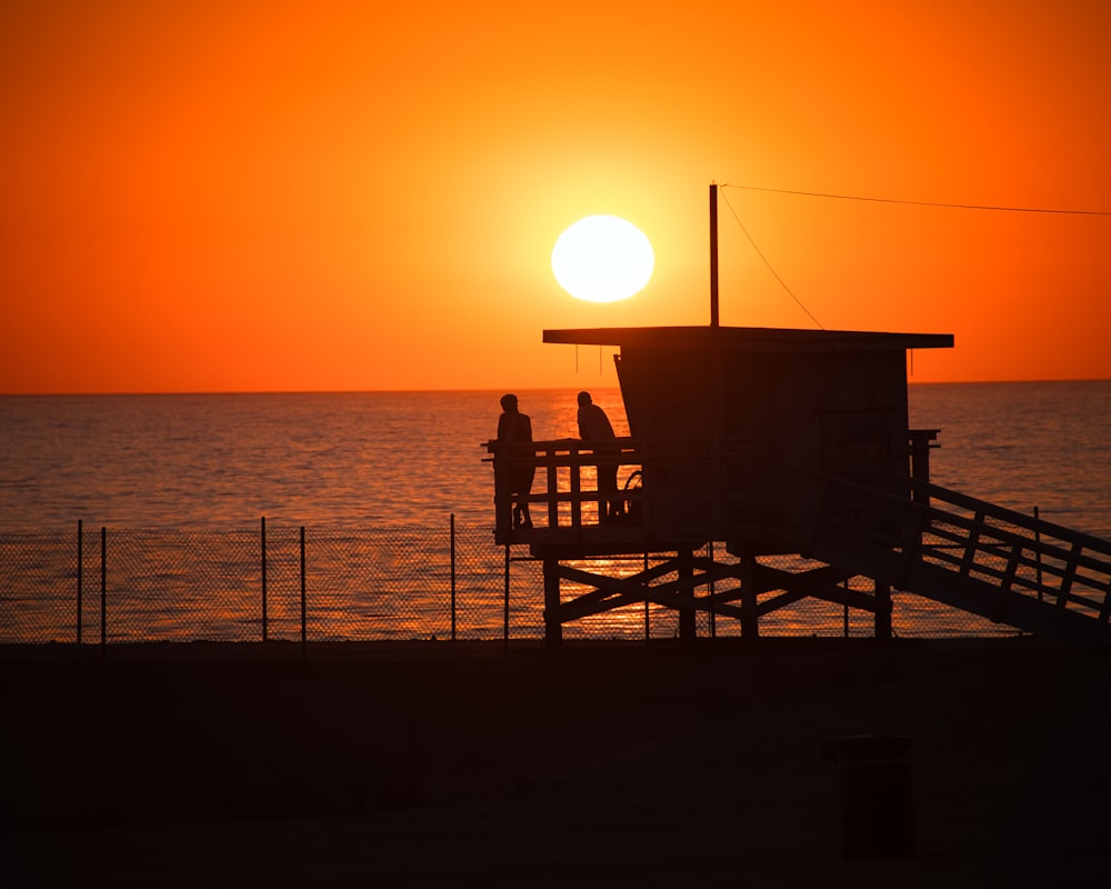 silhouette of wooden lifeguard house on beach during sunset