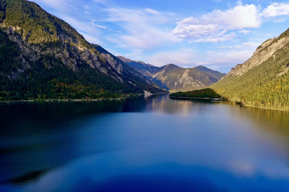 green mountains beside lake under blue sky during daytime