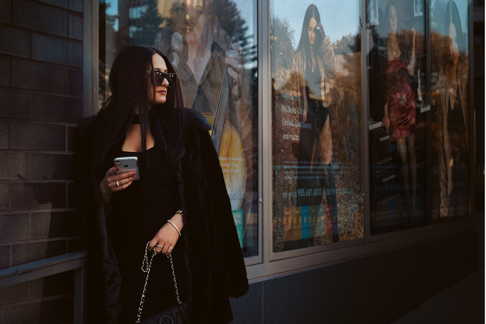 woman in black long sleeve shirt standing beside glass window