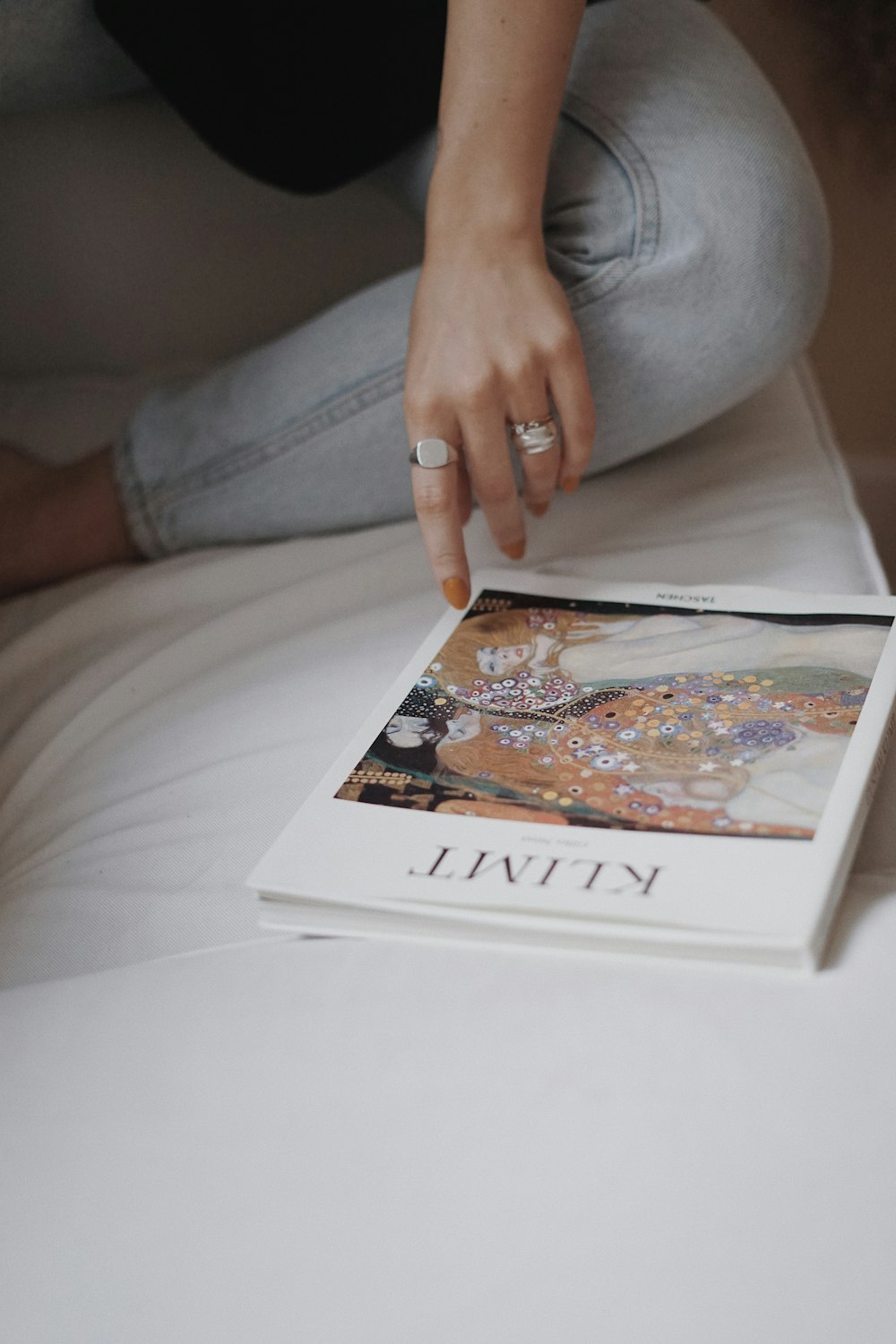 person in gray denim jeans holding white and brown book