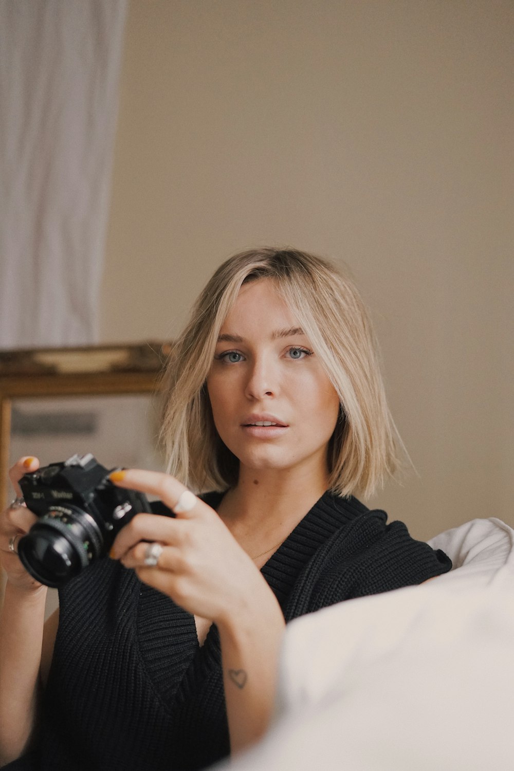 Frau in schwarzem Pullover mit schwarzer DSLR-Kamera