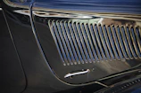 Close-up of a polished chrome grille reflecting dark urban surroundings.
