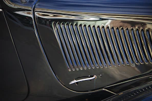 Close-up of a classic car's gleaming chrome grille freshly restored