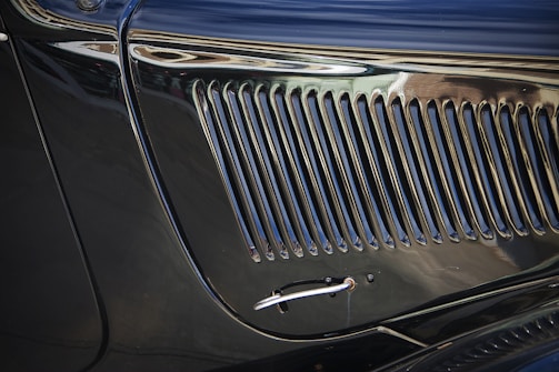 A close-up of a shiny custom car grille reflecting sunlight.