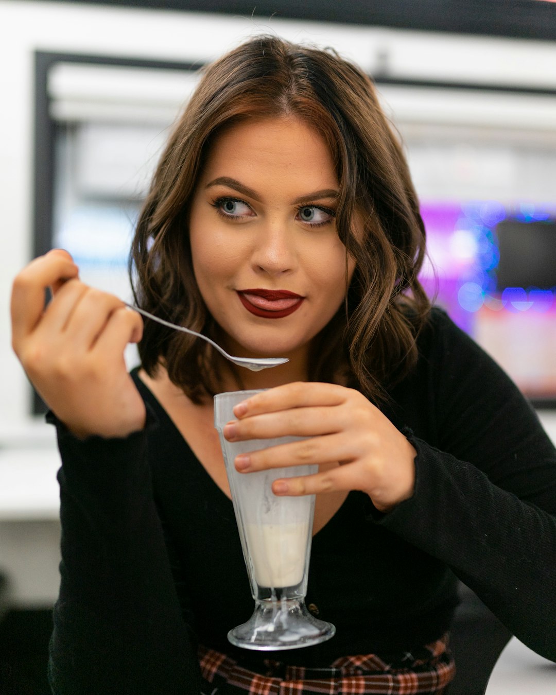 woman in black long sleeve shirt holding clear drinking glass