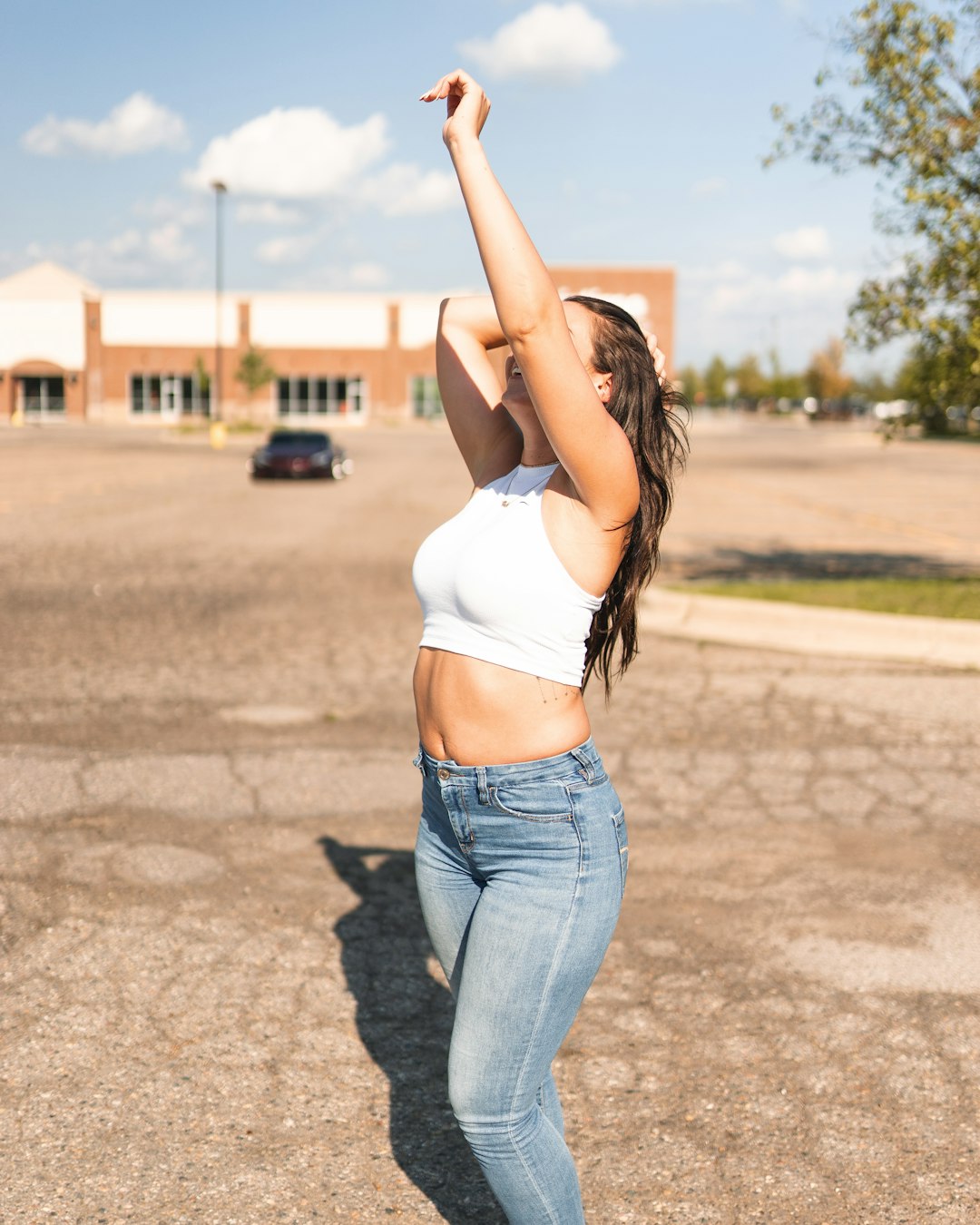 woman in white sports bra and blue denim jeans raising her right hand
